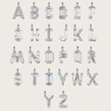 Set of silver alphabet pendants with sparkling gemstones in various cuts, arranged alphabetically on a light beige background.